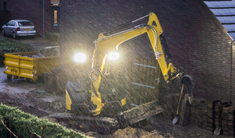 digger working in garden on a dark rainy evening in winter