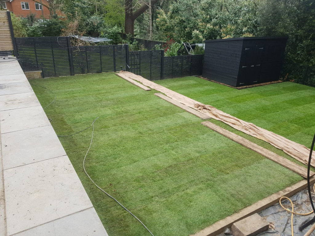 Newly turfed rectangular lawn with laying boards to allow for watering without compacting the soil