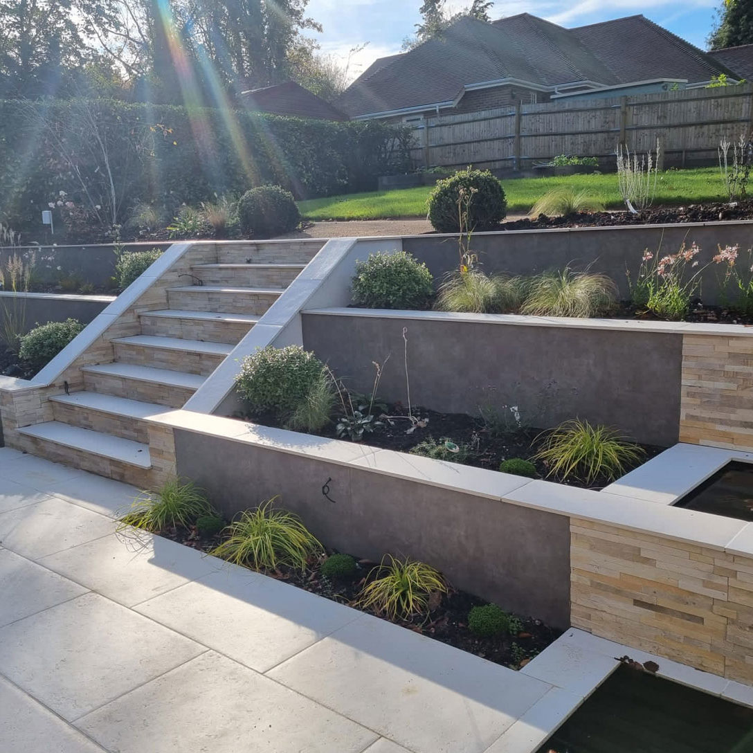 elegant garden with pale coloured porcelain patio and steps to raised terrace with lawn