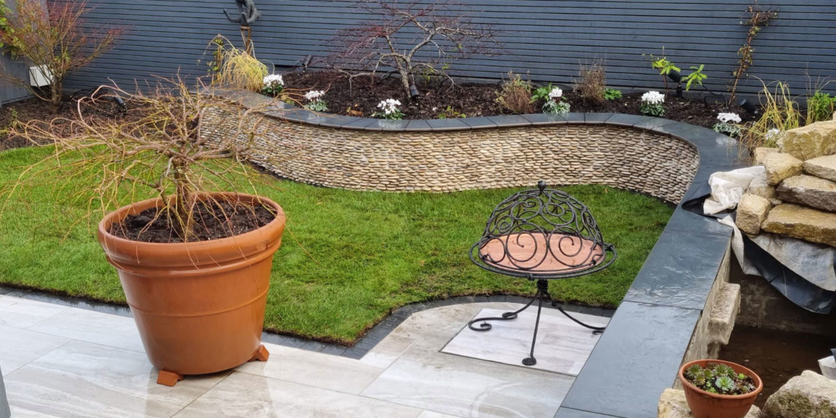 small back garden with elegantly curved raised border with stone cladding